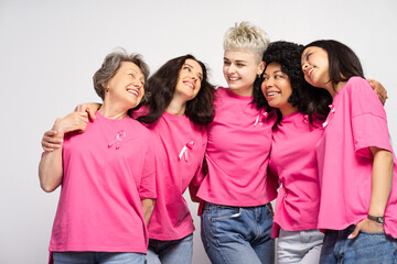 Diverse group of happy women embracing and smiling, showing support for breast cancer awareness