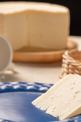Table with rustic utensils and a semi-cured cheese from Brazil, selective focus.