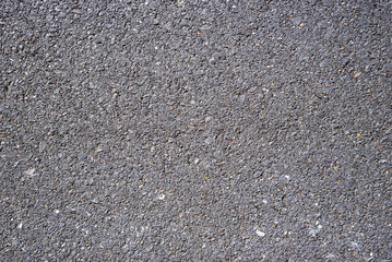 Close-up texture of asphalt surface with visible gravel details and natural cracks, perfect for backgrounds, materials, and urban design elements.