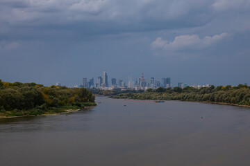 Fototapeta premium View of a city with a river in the foreground against an approaching thunderstorm