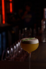 Foamy cocktail in a tall glass in a dark bar