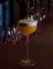 Foamy cocktail in a tall glass in a dark bar