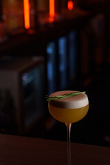 Foamy cocktail in a tall glass in a dark bar