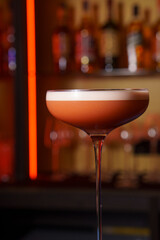 Berry cocktail with foam in a glass in a dark bar
