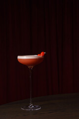 Berry cocktail with foam in a glass in a dark bar