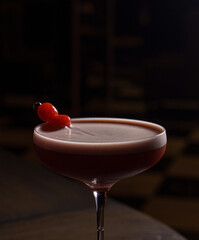 Berry cocktail with foam in a glass in a dark bar