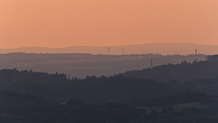 Hilly landscape with wind turbines at sunset, Czech countryside.