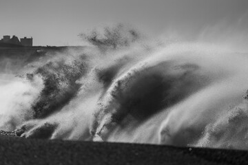 Powerful storm wave crashing, captured in black and white for dramatic intensity.