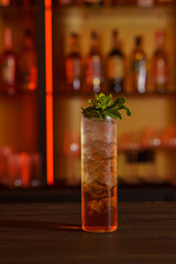 Cocktail in a tall glass against the background of a dark bar