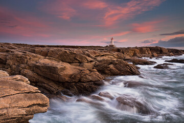 Ploemeur Morbihan Waves crashing against rocky coast at sunset with vibrant pink and orange skies.