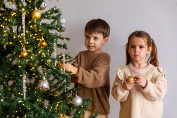 Two children, best friends or siblings are decorating festive Christmas tree in living room at...