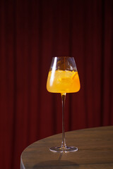 Orange cocktail in a glass goblet in a dark bar