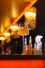 Orange cocktail in a glass goblet in a dark bar