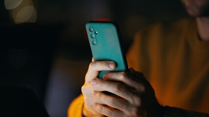 Closeup guy holding smartphone in night home. Smiling man reading cellphone