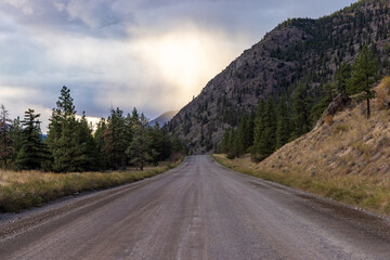Fototapeta premium Dirt Road Through Mountains and Trees at Sunrise in BC, Canada