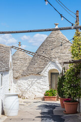 White ancient stone house with conical roof in the unique village Alberobello, Italy.