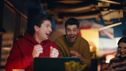 Emotional teammates giving five celebrating achievement at dark office closeup