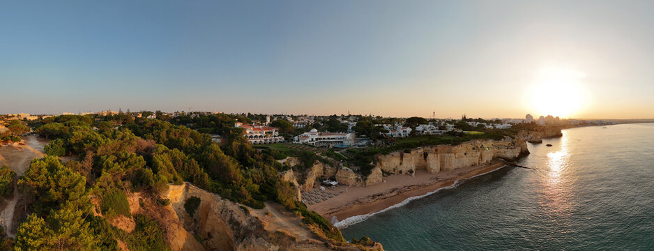Panoramic aerial sunrise view of Algarve coastline, cliffs, and Portimão, Portugal