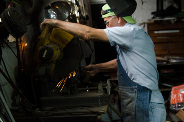 Welder cutting metal with circular saw creating sparks in workshop