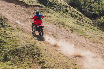 Motocross rider climbing a steep dirt hill in a sunny day