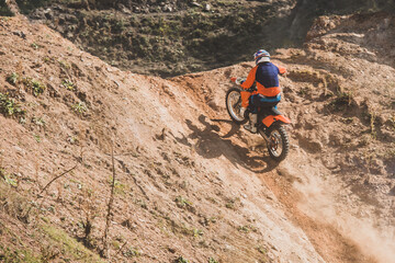 Motocross rider climbing a steep sandy hill in competition
