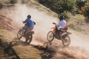 Motocross riders racing up dusty hillside