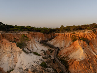 Sunset aerial view of wooden walkway through sandstone cliffs at Praia da Falesia, Algarve, Portugal