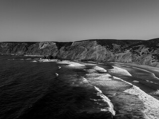 Black and white aerial view of wild beach and cliffs, Algarve, Portugal