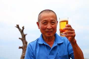 ビール片手に微笑むシニア男性のおじさん