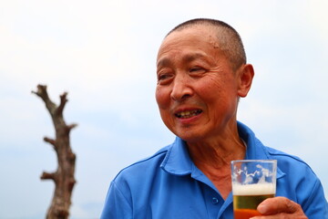 ビール片手に微笑むシニア男性のおじさん