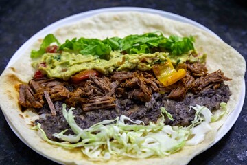 Traditional Mexican food, fajita, tortilla with meat, guacamole, black bean chili and salad
