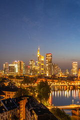 Fototapeta premium Illuminated Frankfurt City Skyline, Residential Buildings, Bridges and Main River at Night. Wide Shot. Aerial View. Blue Hour. Hesse, Germany