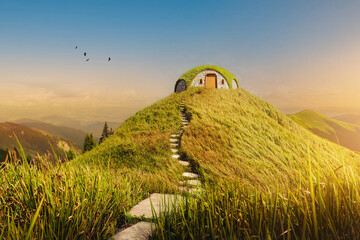 A small, round hobbit-like house with a grass roof on a hill, surrounded by lush greenery and a stone path leading to the door. Birds fly in the clear sky.