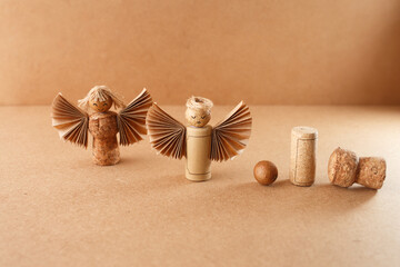 Crafted cork angels with paper wings and twine details on brown surface, perfect for eco holiday...