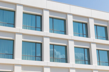 Modern white building showing identical windows reflecting blue sky