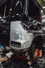 Fototapeta premium A broken car with a violation of geometry is on the frame for straightening. Restoration of cars with a chain and a hook. Repair in a workshop and car service.