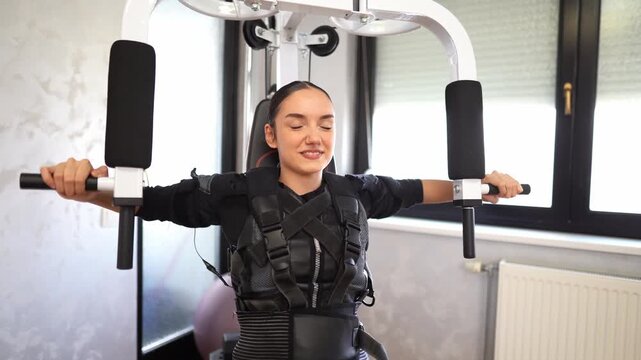 Young woman exercising with ems suit in gym
