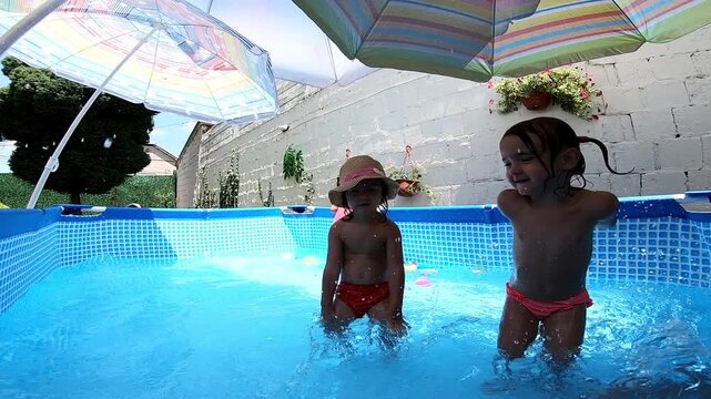 Happy children splashing in a backyard swimming pool