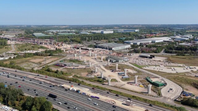 Aerial drone footage of HS2 high speed railway train line construction infrastructure and busy motorway M1 highway traffic, vehicles near Birmingham England UK 