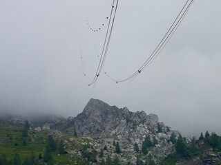 A long exposure shot of high-voltage power lines gracefully suspended above a rugged mountain peak...
