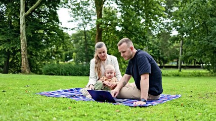 Happy young family with child outdoors using laptop and smartphone. Business family with small child working remotely while walking with child. Freelance family with child in park. - Powered by Adobe