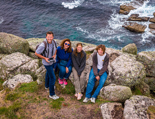 Family of four hiking on a grassy coastal cliff with ocean views