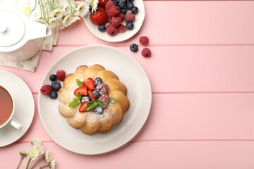 Delicious bundt cake with powdered sugar, berries and mint on pink wooden table, flat lay. Space for text
