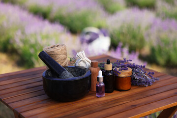 Making natural cosmetics. Beautiful lavender flowers and other ingredients on wooden table in field