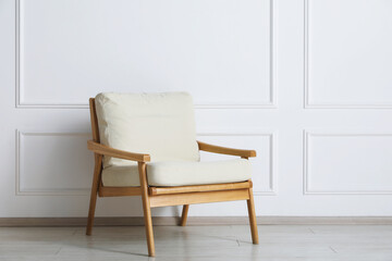 Comfortable beige armchair near white wall indoors