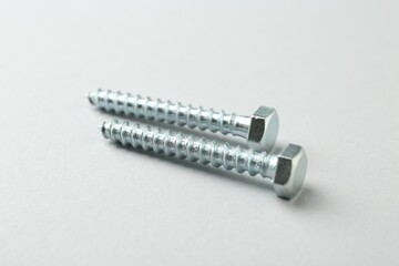 Two metal bolts on light grey background, closeup. Hardware tool