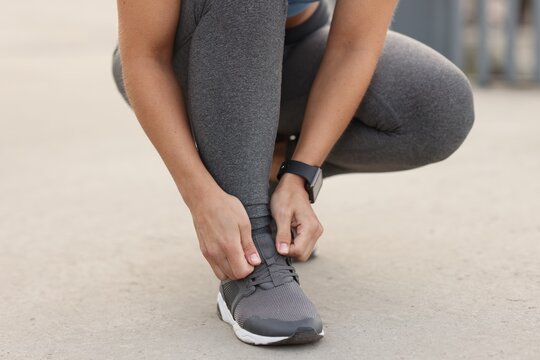 Woman tying shoelaces before running outdoors, closeup - Powered by Adobe