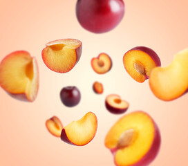 Fresh ripe plums swirling in air against coral gradient background