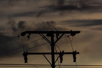 Silhouette of power line with dramatic sky at sunset background.