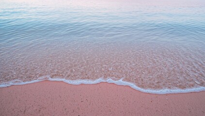 Gentle wave rolls onto soft pink sand beach serene ocean shoreline serenity